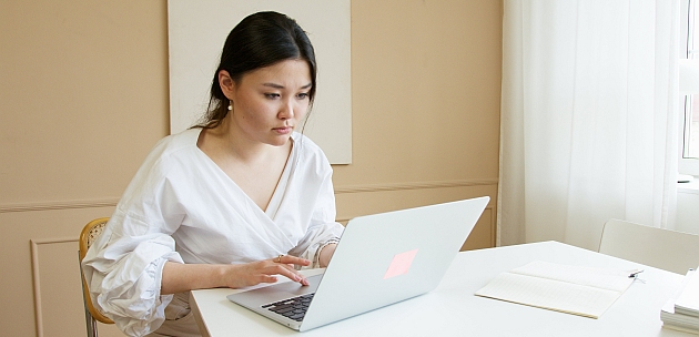 An asian descent woman working on a laptop.